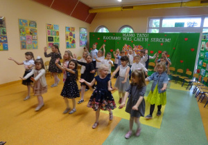 Dzieci tańczą, unoszą ręce przed sobą.